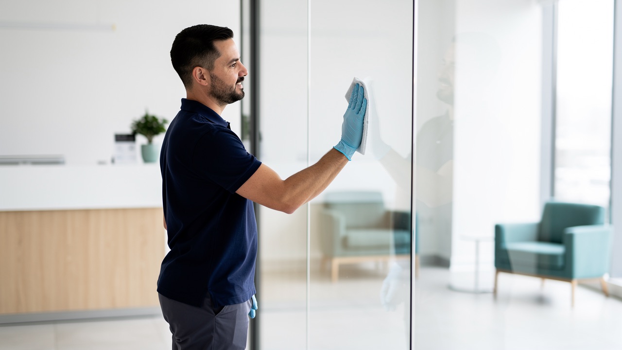DoctorKleen technician wiping a glass partition in a modern medical office